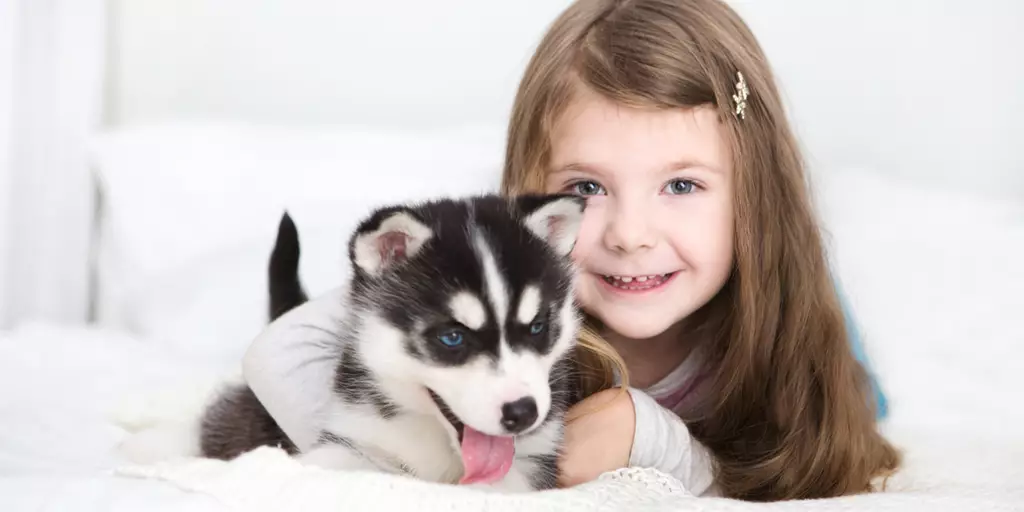 A little girl playing with a newly adopted puppy in his first few days at home.